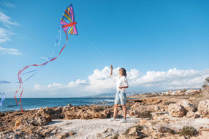 美丽的年轻女子女孩在海边放风筝