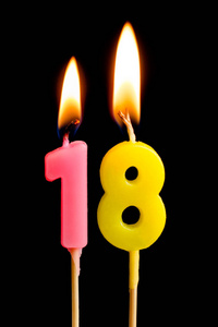 燃烧蜡烛的形式为18十八数字 数字, 日期 的蛋糕孤立的黑色背景。庆祝生日周年纪念日重要日期节日餐桌设置的概念