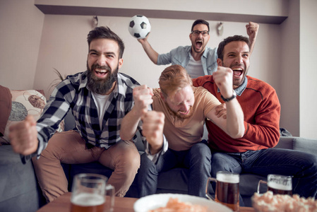 一群朋友足球爱好者观看足球比赛在电视和庆祝目标