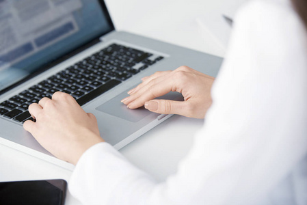 当你坐在办公桌前, 为新项目工作时, 在笔记本电脑键盘上的女商人的手