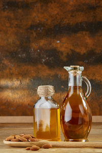 玻璃瓶中的芳香油和在木桌上舀杏仁的瓶子, 特写