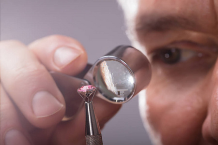 通过放大放大镜对一个人的手检查钻石的特写