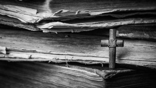棕色十字木背景上的圣经 。圣书。黑白摄影
