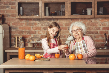奶奶与孙女在厨房品尝橙汁