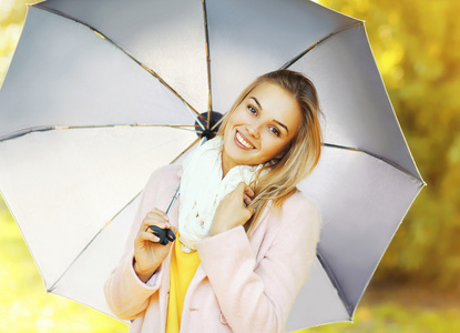 美女微笑着把伞在秋天公园的肖像