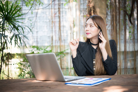 年轻的女商人坐在她的工作场所, 在电话里聊天