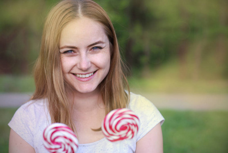 Portret 闭上可爱的年轻女子抱着 Lolipop o 糖果, 只是被绿园背景