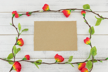 空白棕色卡片装饰用假的红色花分支在白色木头背景