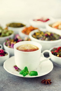 茶概念与复制空间。白陶碗中不同种类的干茶与灰色背景下的芳香茶杯