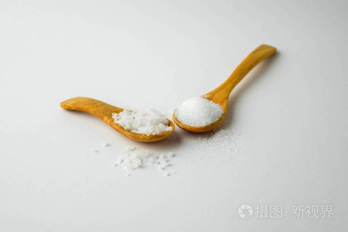 盐和糖在白色背景上的小木勺