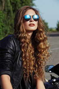 皮革服装和太阳镜附近一辆摩托车的年轻女子