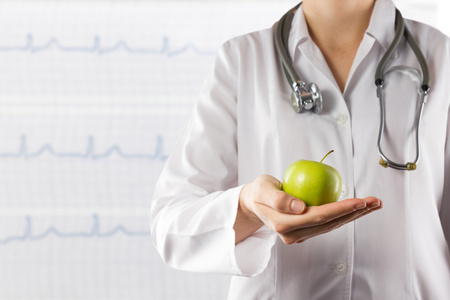 女医生的手拿着绿色的苹果。近摄镜头上模糊的医学背景。医疗保健和医学的概念。复制空间