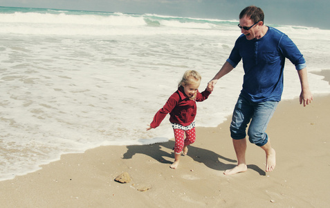 父亲和女儿走在沙滩上