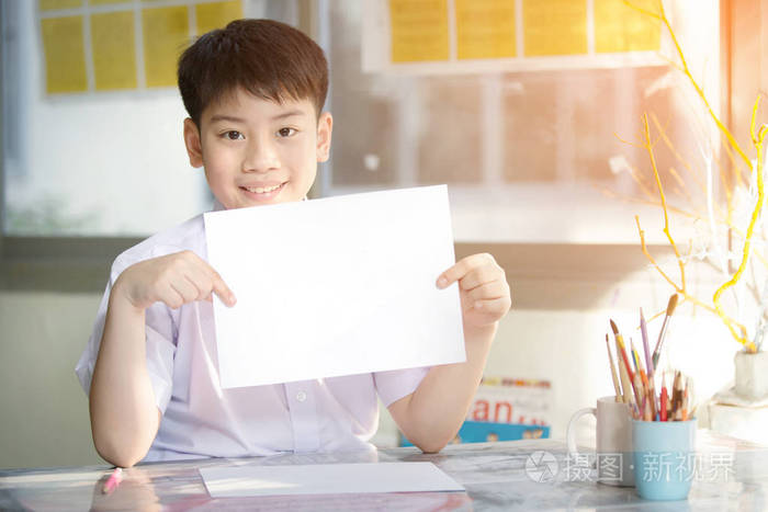 快乐的亚洲男孩手拿着空白的a4纸看着
