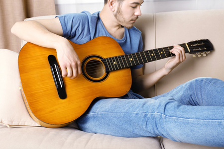吉他在房间里的沙发上的年轻人