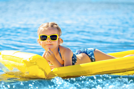 游泳在充气沙滩床垫上的小女孩