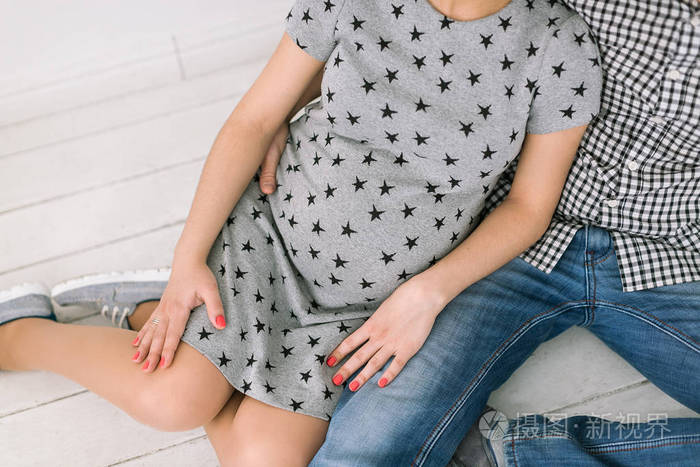 的肚子的年轻未来的母亲,年轻人期待着妈妈和爸爸坐在白色的木地板上