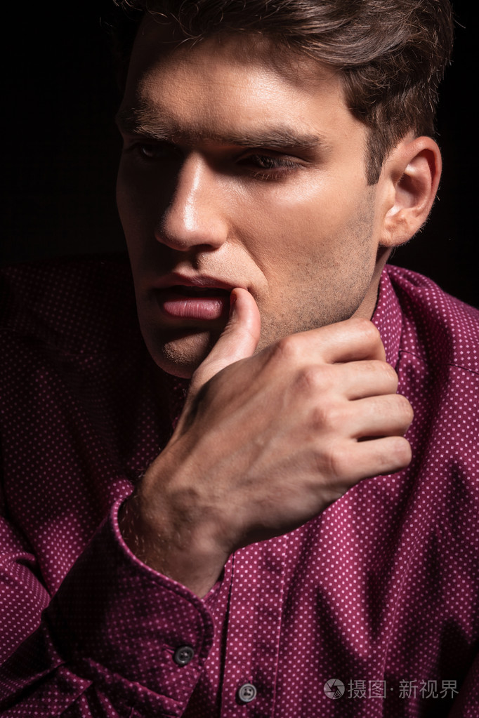 年轻男人他的拇指指向他的嘴唇