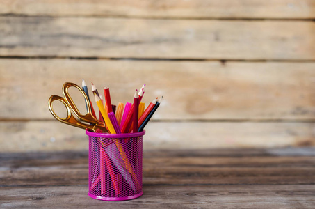 剪刀和彩色铅笔的紫黄色粉红色红色和橙色在固定杯木桌和背景。Copyspace 学校概念