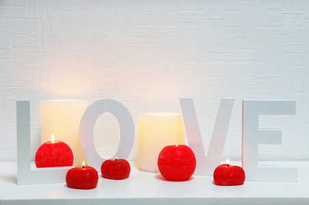 浪漫静物爱词与蜡烛灯在壁炉架上，白色的背景墙上
