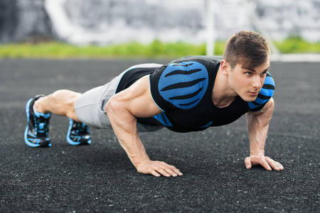 场内做俯卧撑在体育场内,交叉训练锻炼的健美男子.