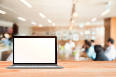 空白的屏幕的笔记本电脑放在白色的木桌，在模糊的人，在蒙太奇产品目前的模糊商业摊派背景