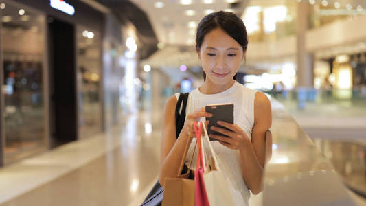 智能手机使用购物袋的女人