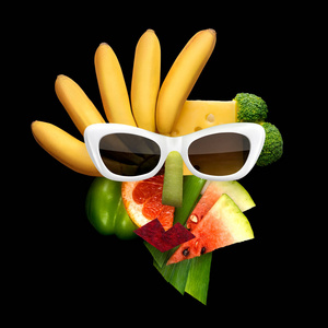 美味的艺术。立体派风格女性脸太阳镜由水果和蔬菜，在黑色背景上的古怪食品的概念
