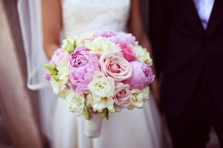 新娘抱着美丽的牡丹和玫瑰花束