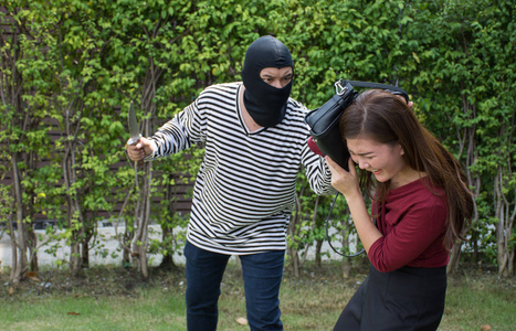 男性女性牵手举起亚洲男性的强盗遇到抢劫手提包/恐吓用刀向受惊的