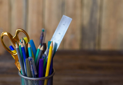 紫黄灰绿色和蓝色在木桌和背景上的固定杯子的彩色铅笔。Copyspace 学校概念