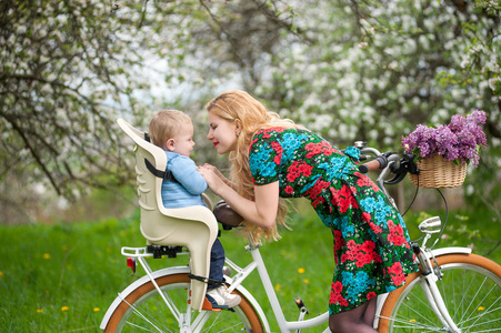 金发女性与城市自行车与婴儿在自行车的椅子上