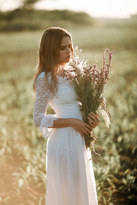 年轻女子在长长的白色花边礼服上的麦田