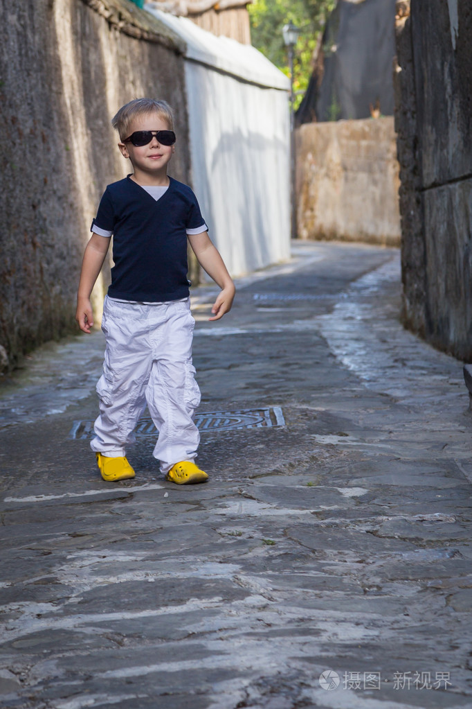小男孩戴着眼镜在街道上的旧城