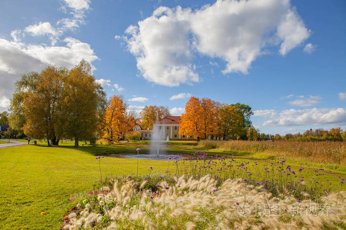 用鲜花和喷泉老庄园附近的草地上的秋园明亮的秋天时间