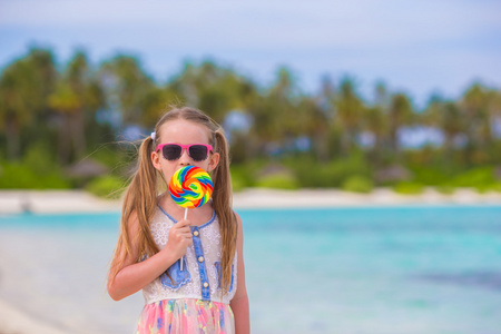 可爱的小女孩在海滩上玩得开心棒棒糖