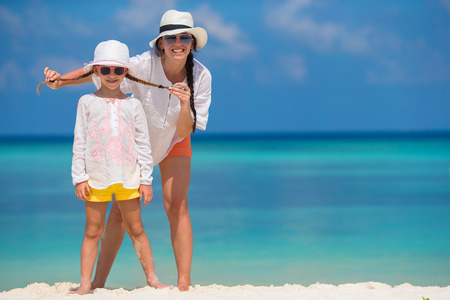 小女孩和年轻母亲在海滩度假
