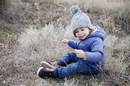 暖和的衣服，坐在草地上的男孩