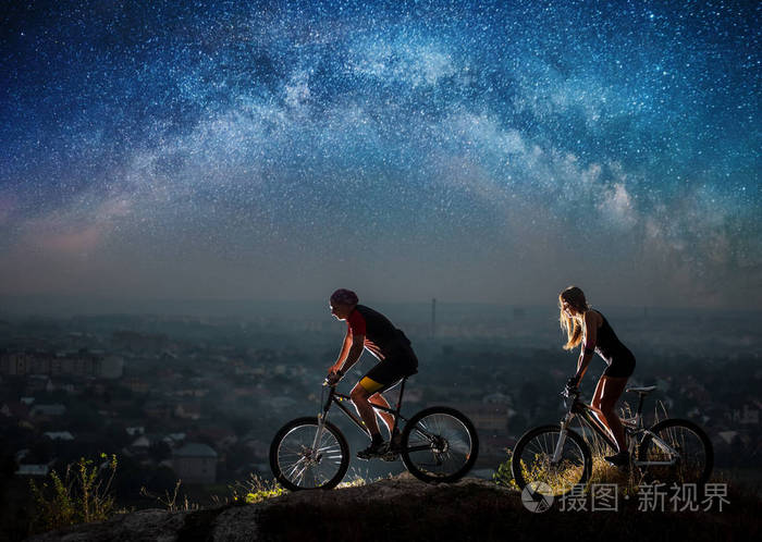 星空下的夜间骑自行车的运动夫妇