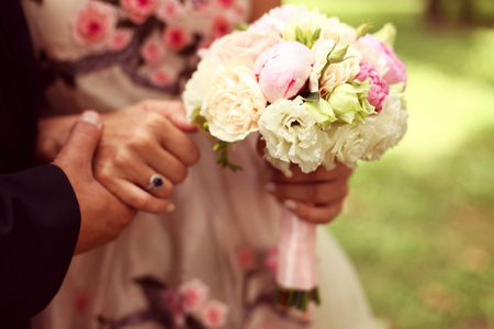 新娘和新郎手牵着手。新娘抱着美丽的婚礼花束