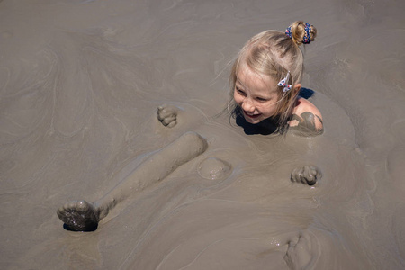 小女孩在海边上的泥火山中沐浴照片