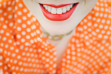 肖像户外年轻漂亮的女孩在橙色时髦金发明亮开朗圆点毛衫，微笑红丰满圆润的嘴唇上的绿草背景