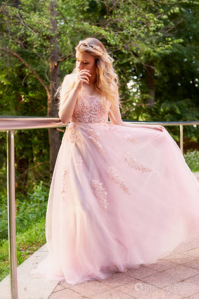 肖像的一个美丽的新娘金发碧眼的女孩在粉红色蕾丝礼服, 头发装饰