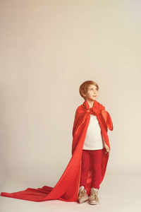超级英雄女孩摆在工作室里披着红斗篷