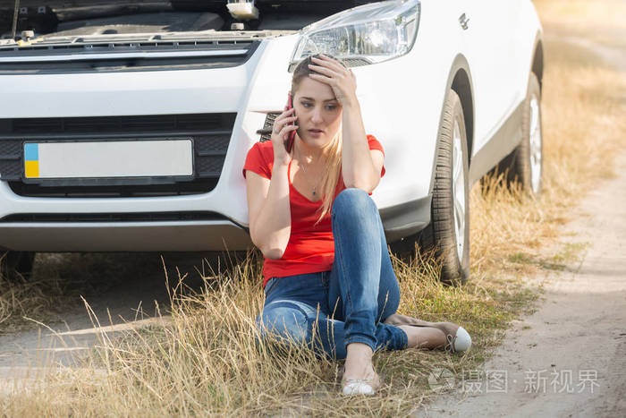 年轻的女人坐在旁边的破车和呼唤诀窍