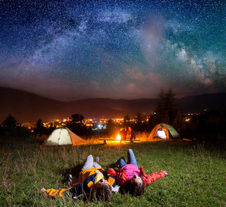 徒步旅行者享受明亮的星星，躺在草地上