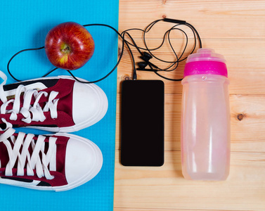 在瑜伽垫上，瓶水 苹果和智能手机上运动鞋