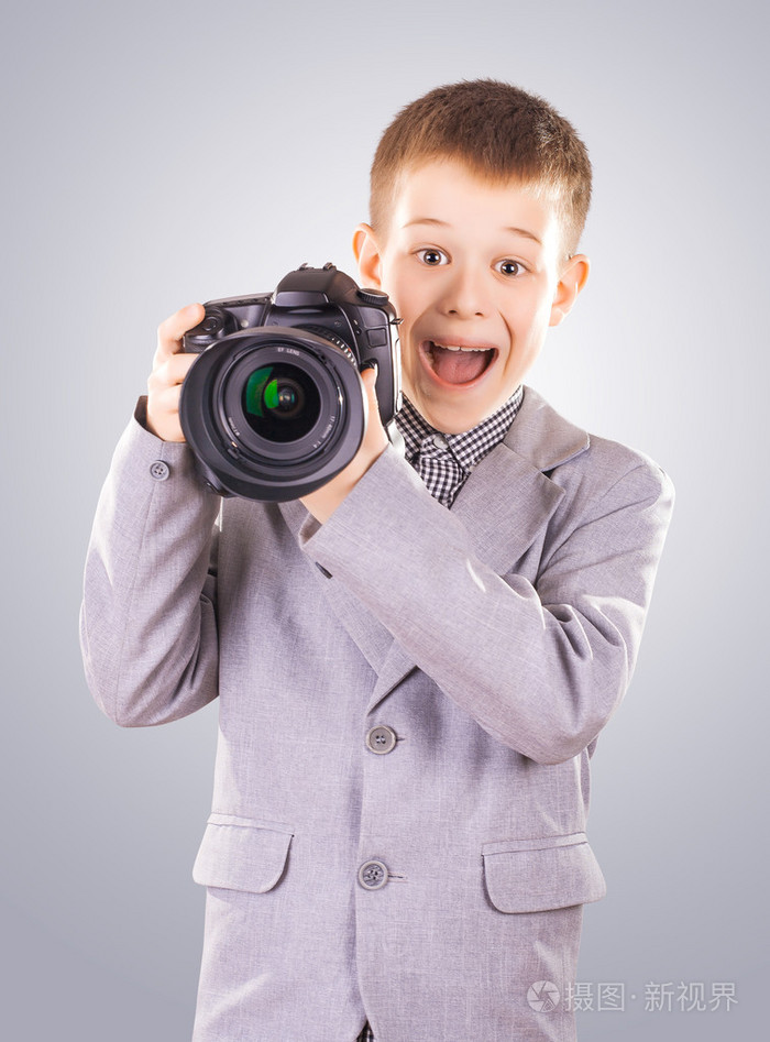 拿着单反照相机在蓝色背景上的孩子照片-正版商用图片