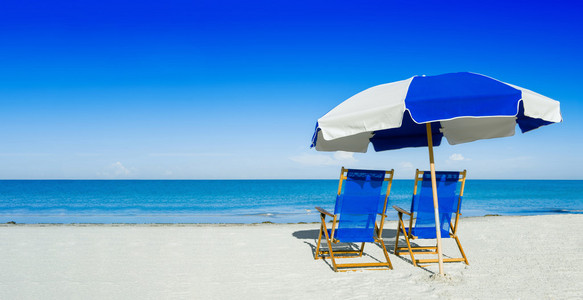 日光躺椅和海滩伞上银砂 度假概念