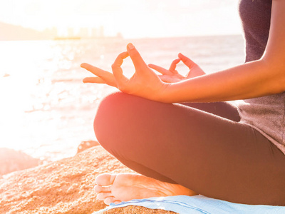 瑜伽的概念。练习在日落海滩上的莲花造型的特写女人手